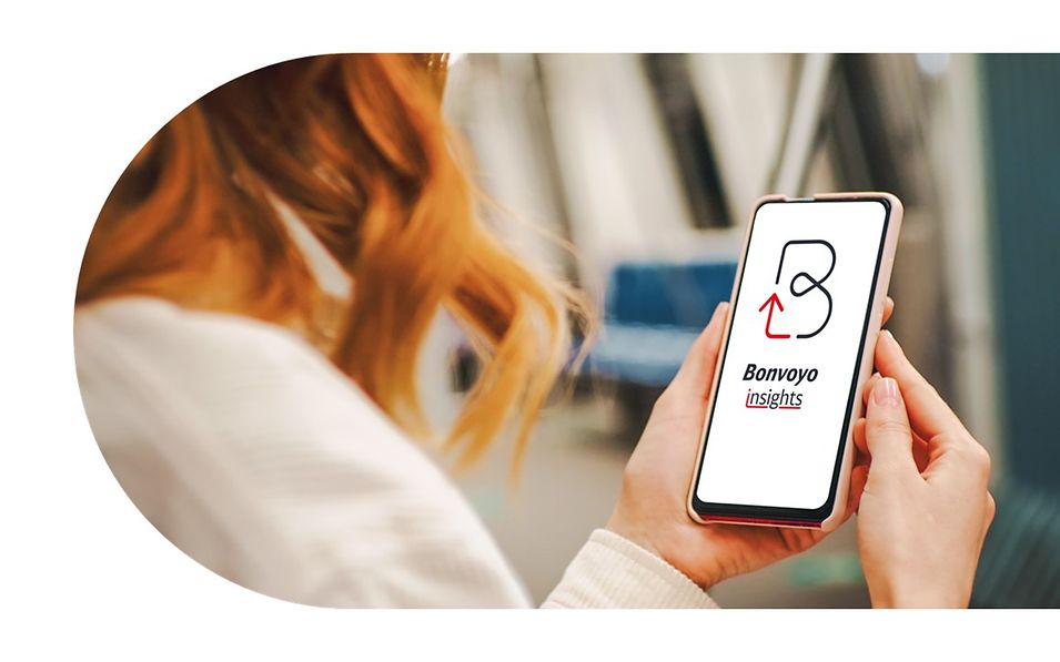 Rothaarige Frau in U-Bahn hält Smartphone und schaut auf geöffneten Bonvoyo insight Screen